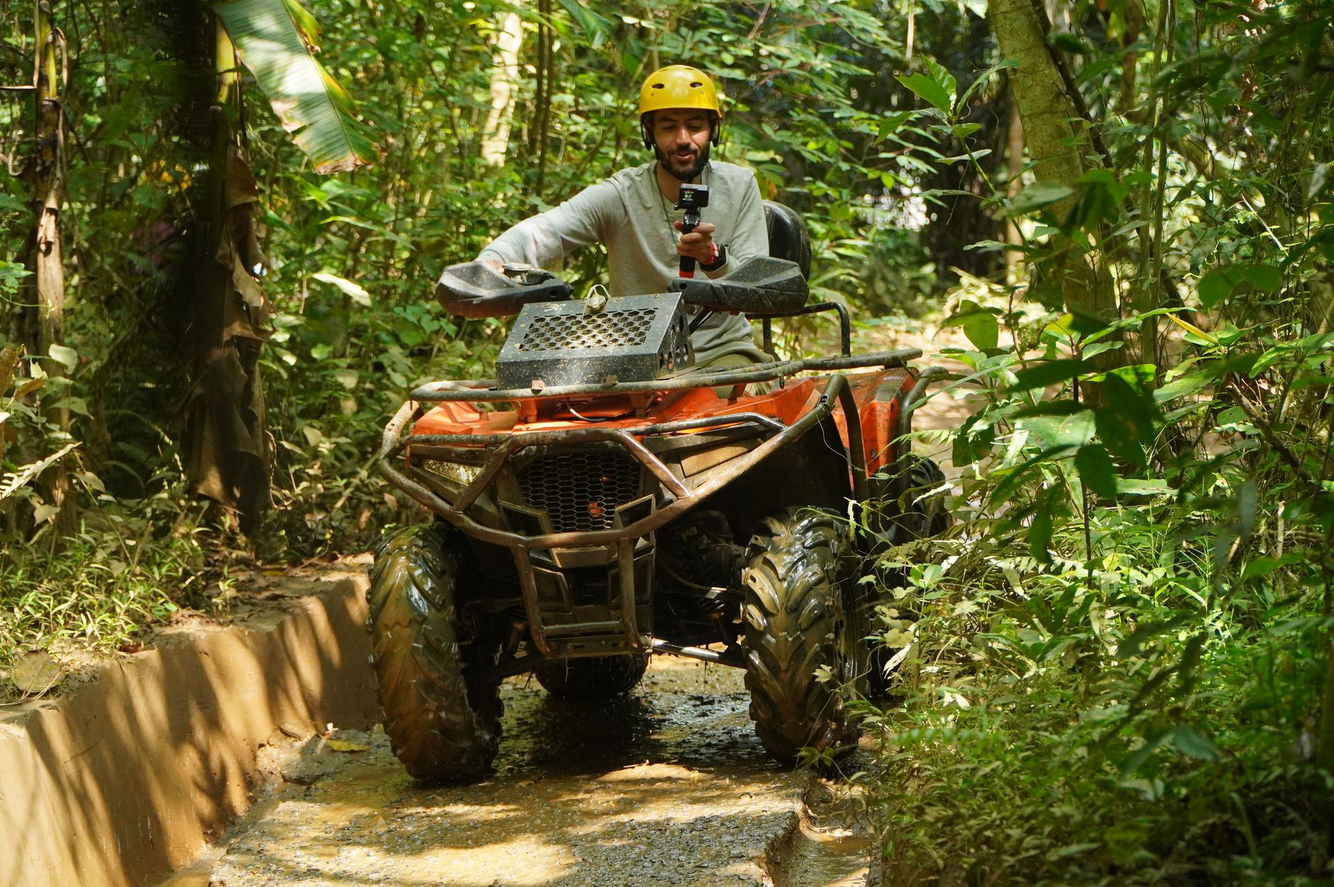 man riding atv through tropical forest trail